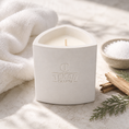 Load image into Gallery viewer, White candle in a decorative holder with 'Texan Crafts' branding, surrounded by a towel and cinnamon sticks on a light surface.
